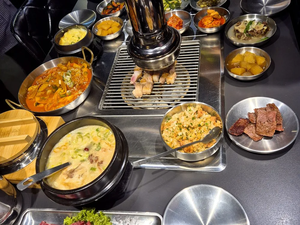 청담채 테이블 한 상 — 구이판을 중심으로 반찬과 찌개, 고기가 차려진 상차림